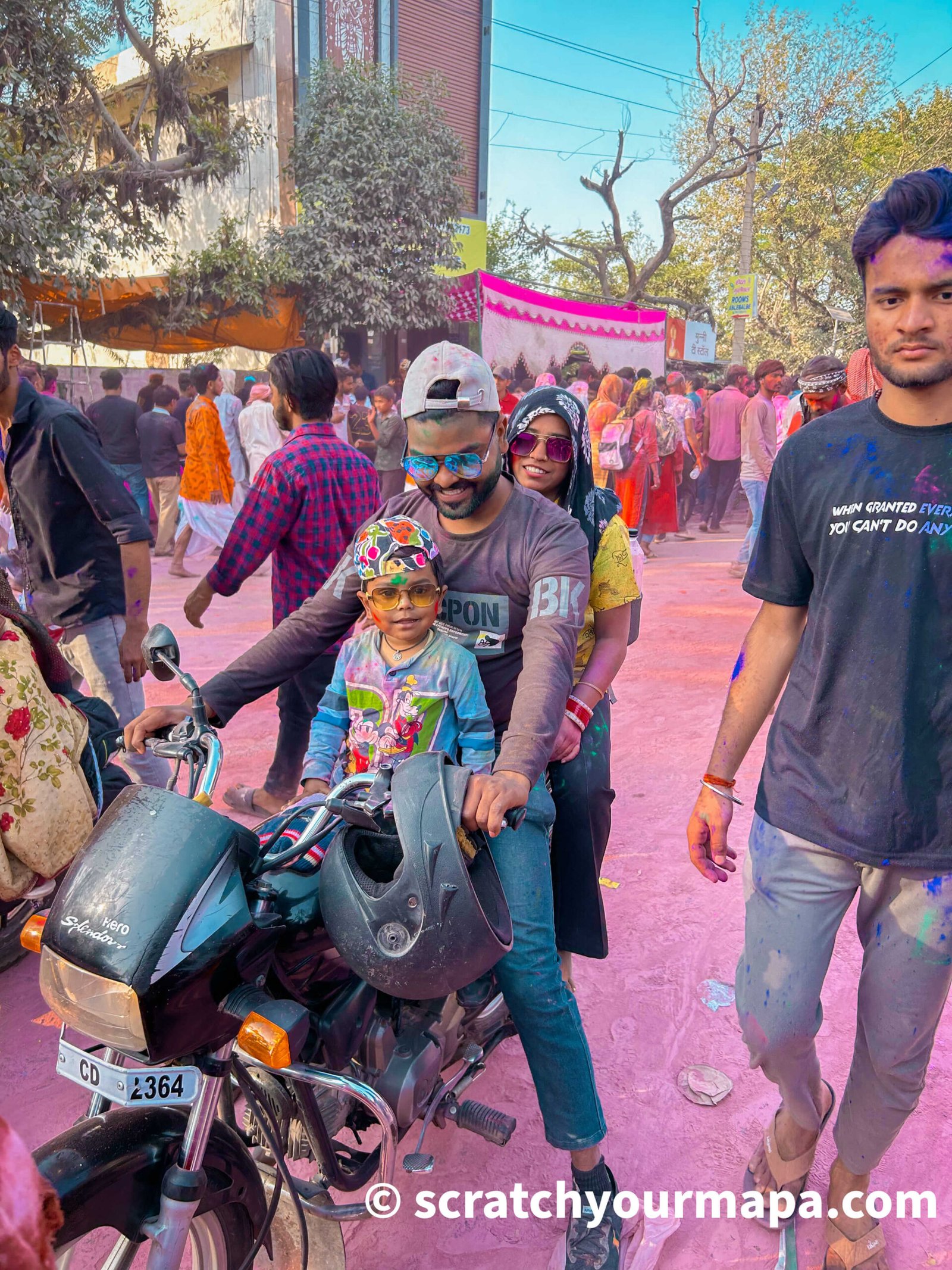 man and his baby on a scooter during Holi festival in India