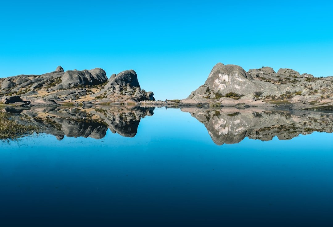 A body of water surrounded by rocks and a blue sky