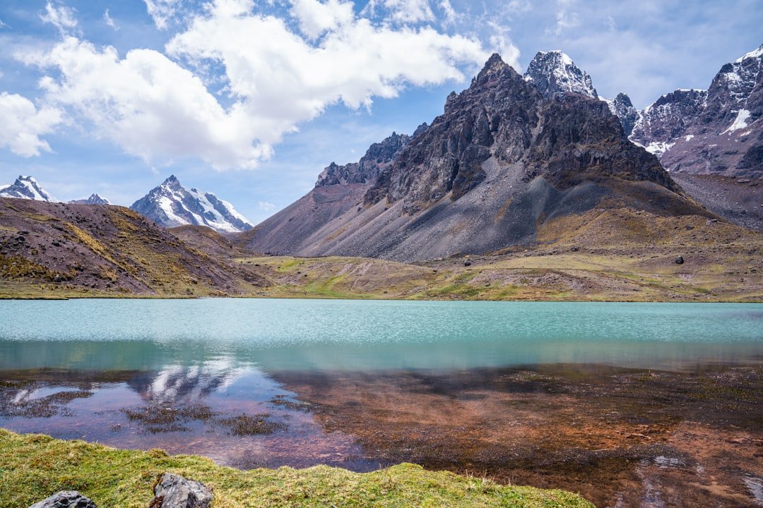 a lake surrounded by mountains under a blue sky